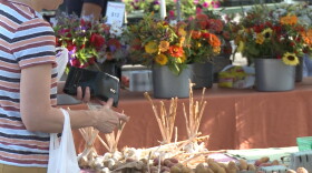 People shop at a farmers' market set up by Bloomingfoods