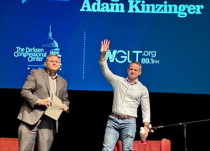 Two men stand on a stage with a WGLT and Dirksen Congressional Center logos int he background. 