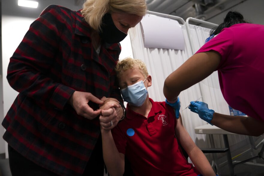 Heather Haworth, left, holds the hand of her 12-year-old son Jeremy as he receives the first dose of the Pfizer COVID-19 vaccine from medical assistant Gloria Urgell at Providence Edwards Lifesciences vaccination site in Santa Ana, Calif., Thursday, May 13, 2021. The state began vaccinating children ages 12 to 15 Thursday. (AP Photo/Jae C. Hong)