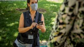 A masked US Census taker takes notes in the field