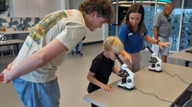 FILE: Staff member Amanda Shuman, second from right, instructs visitors using microscopes in the biomedical and immunology teaching laboratory at the Mote Science Education Aquarium, Monday, Oct. 6, 2025, in Sarasota, Fla.