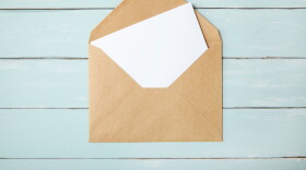 An open brown envelope with letter on a blue wooden desk top background