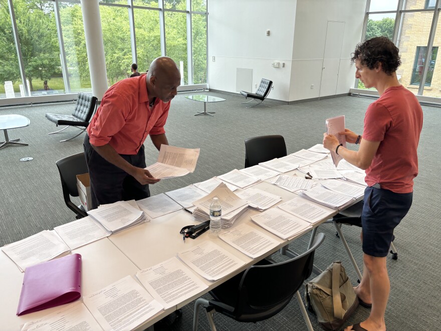 Carlos Buford, left, stands next to a table with piles of papers that all have signatures for the qualified immunity ballot petition.