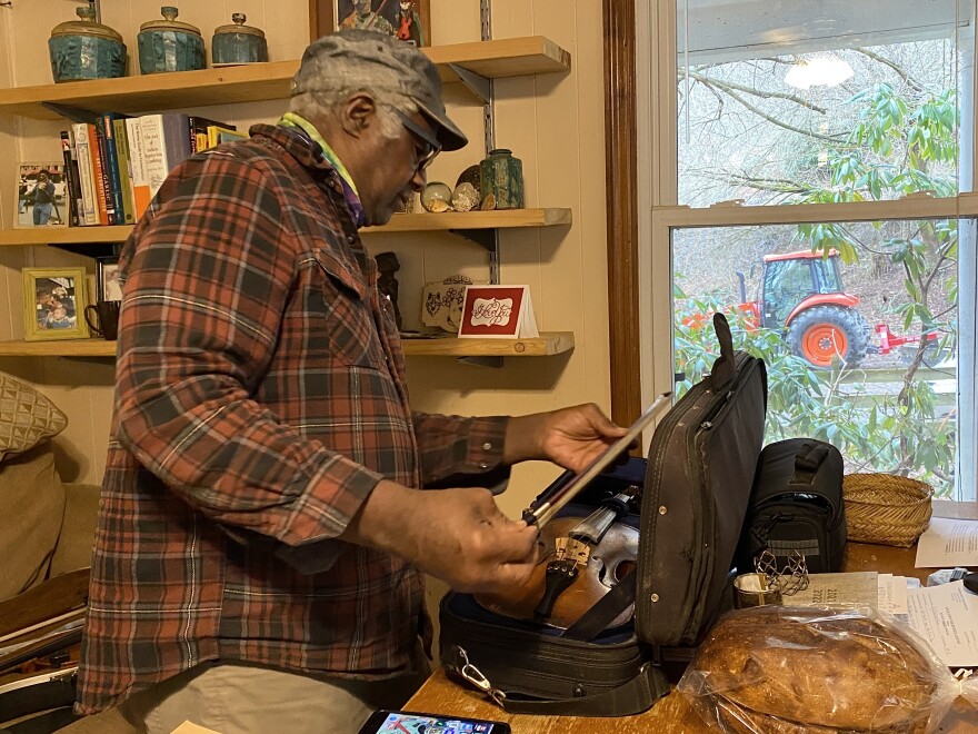 Earl White checking the bow of one of his fiddles.