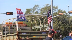 Trump supporters stand in front of a large, military-style truck at the front of the "Trump train."
