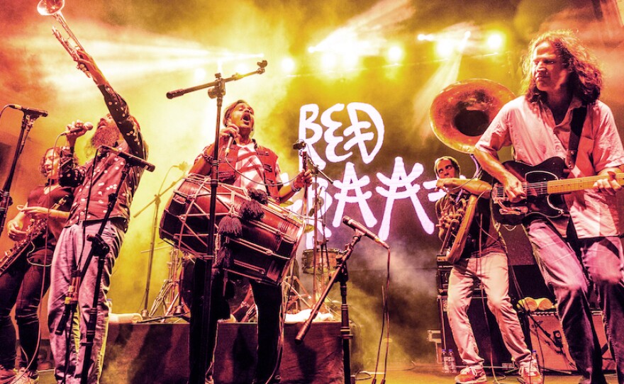 Five members of Red Baraat perform on stage holding instruments.