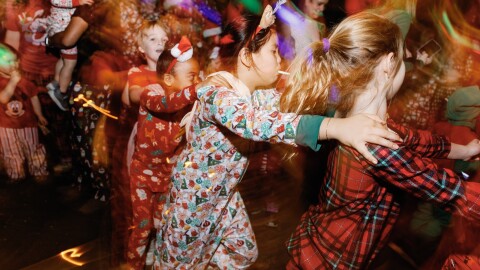 kids in holiday pajamas dancing in a conga line