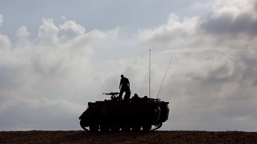 An Israeli soldier stands on a military vehicle near Gaza early Tuesday, when a cease-fire was meant to take effect. The deal hasn't been embraced by all of Hamas.