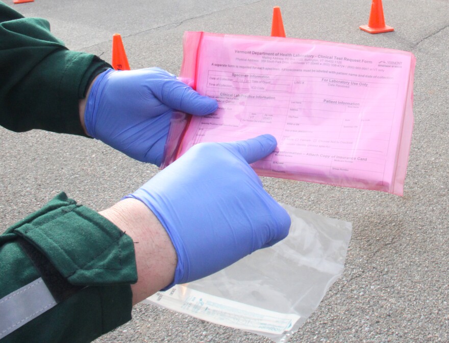 Gloved hands pointing to a card in pink plastic.