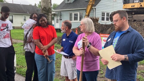 Tom Fisher-King (center), CEO of Habitat for Humanity Quad Cities, looks to new homeowner Hugette during a ceremonial groundbreaking in East Moline, Aug. 15, 2026. Looking on are Zach Currier, Habitat family services coordinator, and Hugette's voilunteer mentor, Belinda Holbrook.