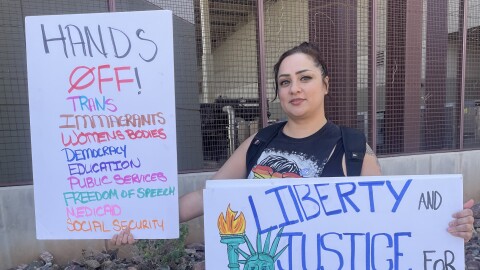 Protester Liahla Ferra holds a pair of signs at the "Hands Off!" protest against the Trump administration on Saturday, April 5, 2025, in downtown Phoenix. Speaking about her concerns, Ferra said "there's too much to put on one poster."