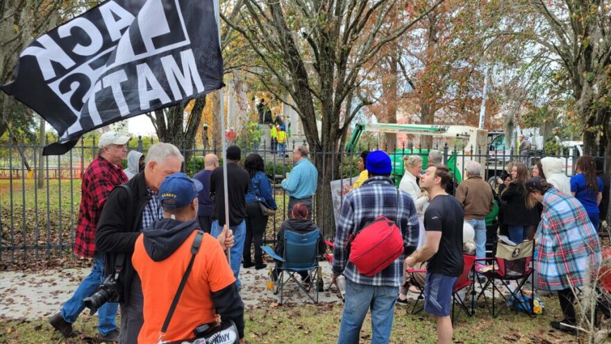 People stand around a gated park.