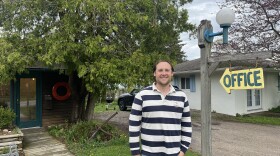 George Brittain, standing outside the office of the Anchor Inn on West Bay in Traverse City. It’s a renovated historic motel, just across the road from the beach. (Photo: Claire Keenan-Kurgan/IPR News)