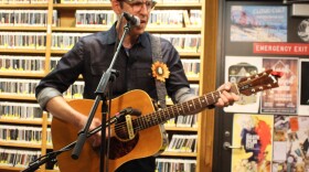 Man playing and acoustic guitar and singing into a microphone