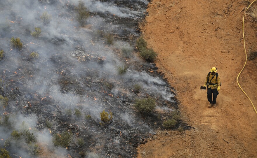 A firefighter walks along a containment line while battling a wildfire in Redding, Calif., on July 28.