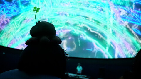One of the attendees watches the DJ and the light show during the rave at the Challenger Center Fogg Planetarium.
