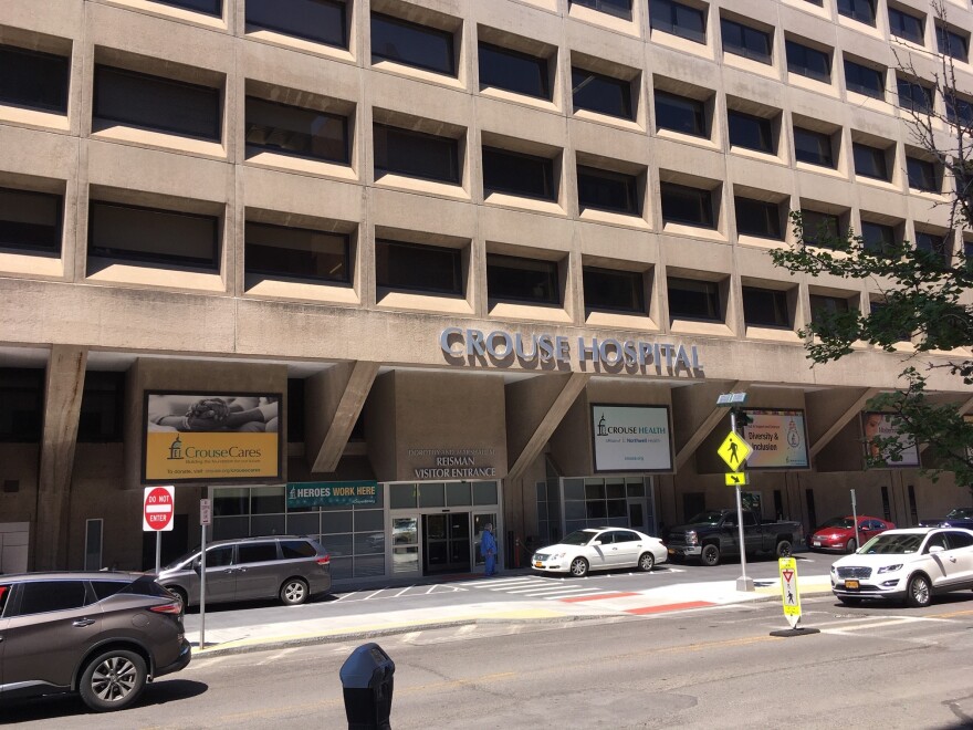 A concrete multi-story building on the side of a street with the words "Crouse Hospital" on the exterior.