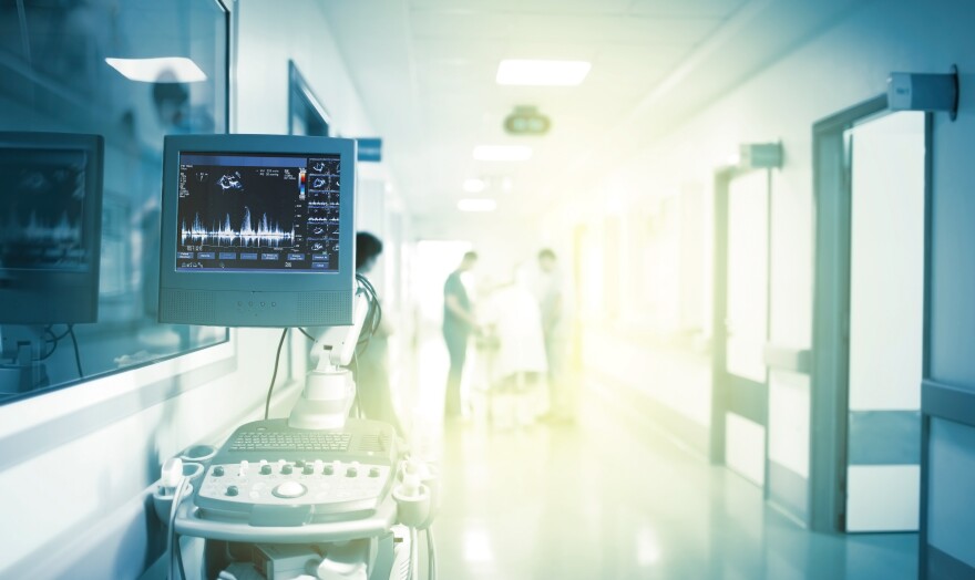 Fantastic light in the hospital hallway with a medical examination machine with patient nurses doctors.