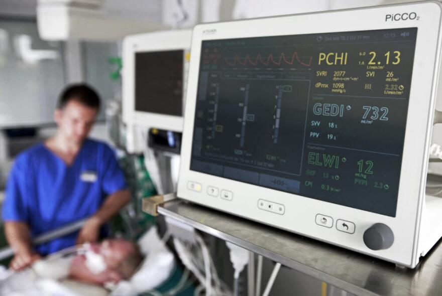 A male nurse sits at a patient's bed at the intensive care unit in the  hospital. (Jens Meyer/AP)