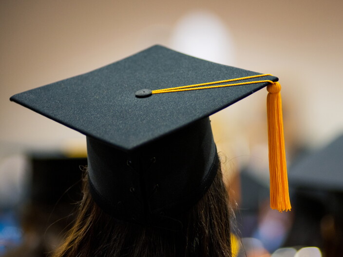 A student stands in a graduation cap.