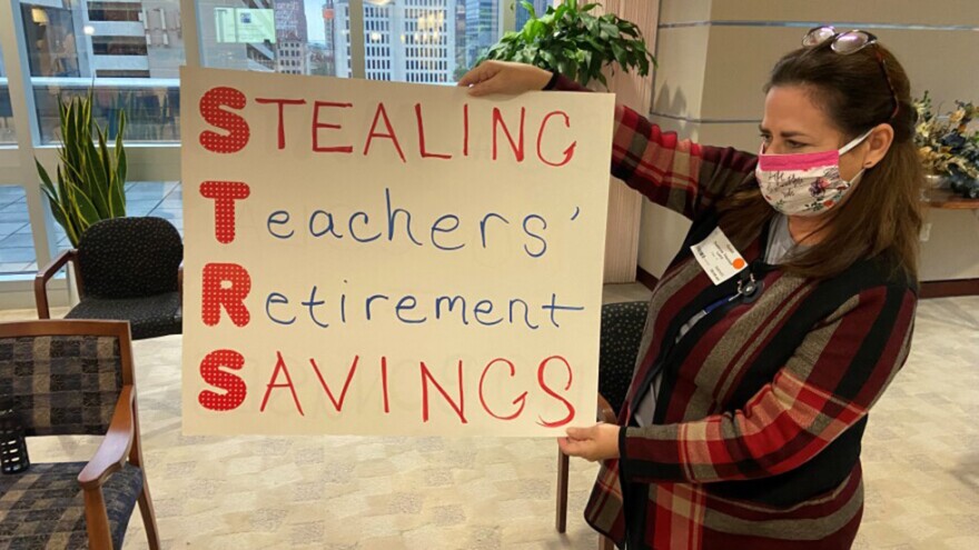 Suzanne Laird holds a sign that she says she’s brought to STRS board meetings for years, after the board voted to suspend cost of living adjustments for benefit recipients. STRS says it pays out over $7 billion in benefits each year to more than 152,000 retirees, survivors and others. [Karen Kasler / Statehouse News Bureau]