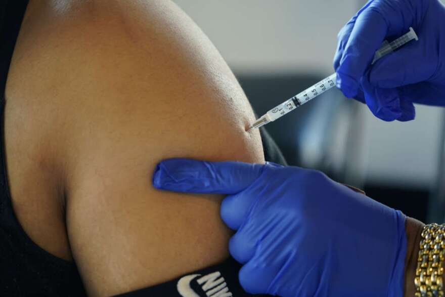 FILE - A Jackson, Miss., resident receives a Pfizer booster shot from a nurse at a vaccination site Feb. 8, 2022. The Biden administration hopes to make getting a COVID-19 booster as routine as going in for the yearly flu shot. (AP Photo/Rogelio V. Solis, File)