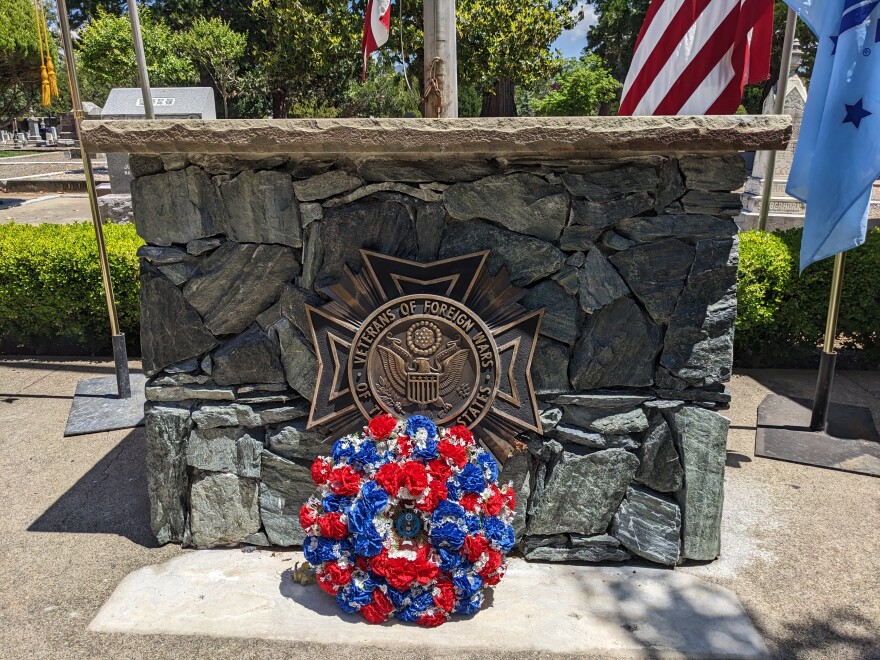  A red, white and blue wreath in front of a monument to the Veterans of Foreign Wars.