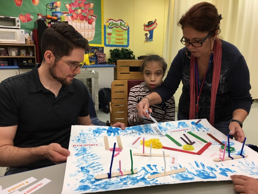 Donald Welch, left, helps a student at Brucie Ball Educational Center create poetry.