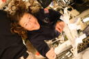 NASA astronaut Christina Koch smiles at the camera as she holds a pipette and saliva booklet for the Artemis II Immune Biomarkers study. Samples will be analyzed for proteins, enzymes, and other biomarkers that monitor immunity, inflammation, nutritional status, bone health, and radiation effects, to determine how crewmembers adapted to deep spaceflight conditions.