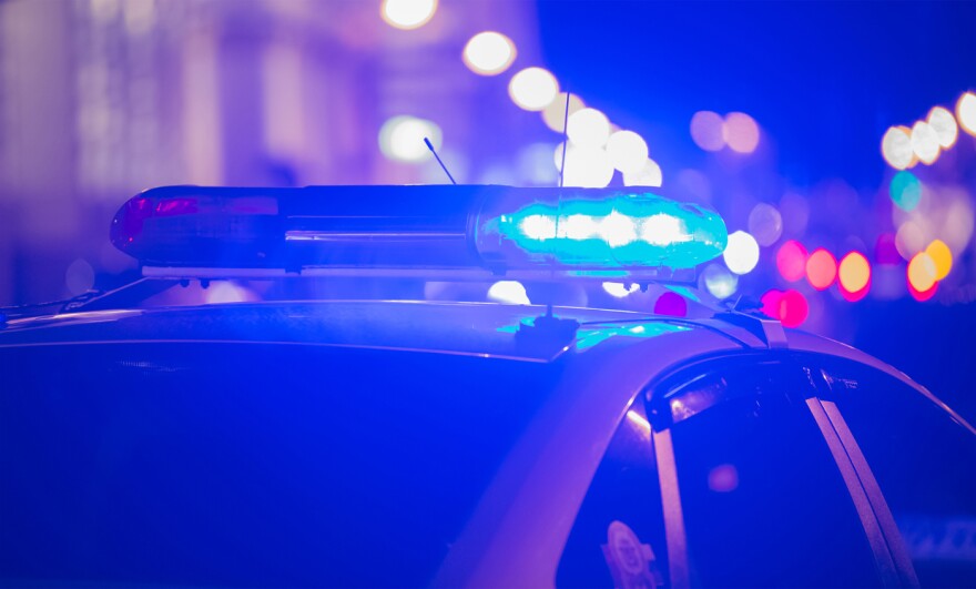 Blue light flasher atop of a police car. City lights on the background.