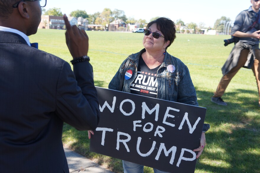 woman holding sign that says women for trump