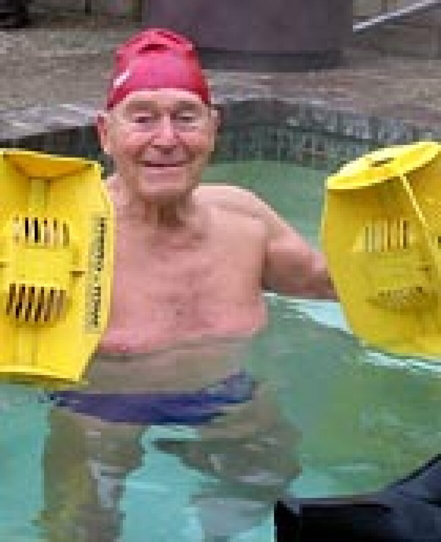 Jack La Lanne in his outdoor Jacuzzi during his daily early-morning workout. He's holding water-resistance devices that create drag.