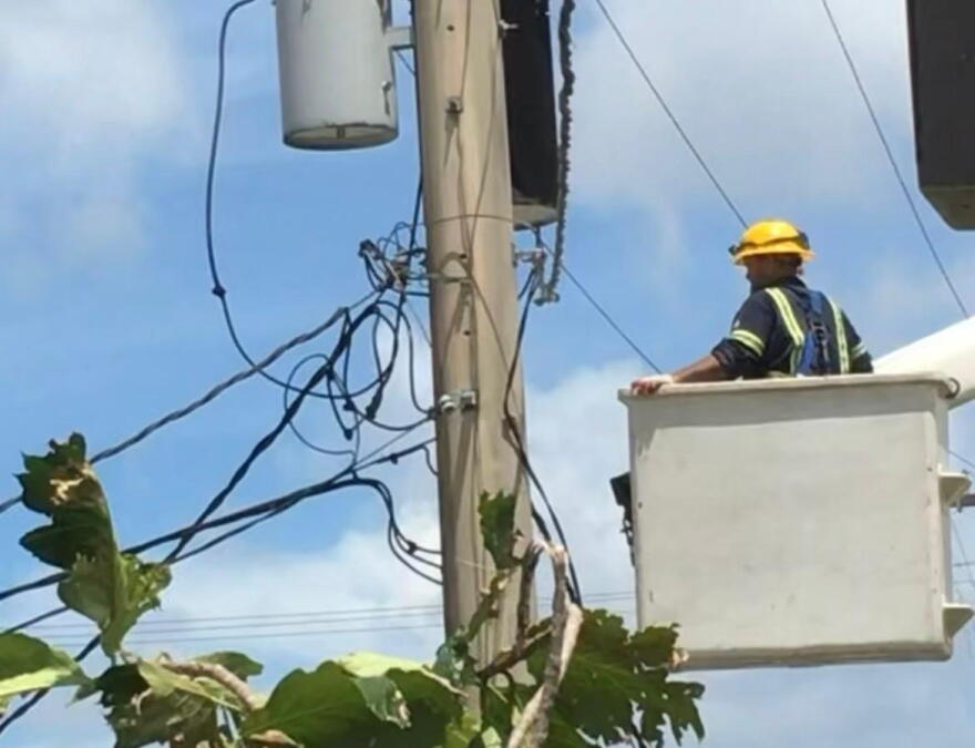 A Guam Power Authority works to restore electricity after a storm.