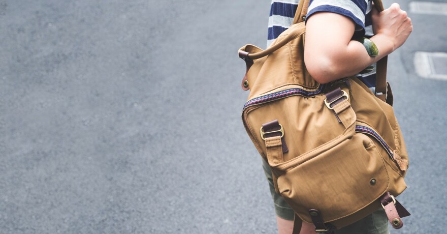 a person walks with a backpack slung over the right shoulder