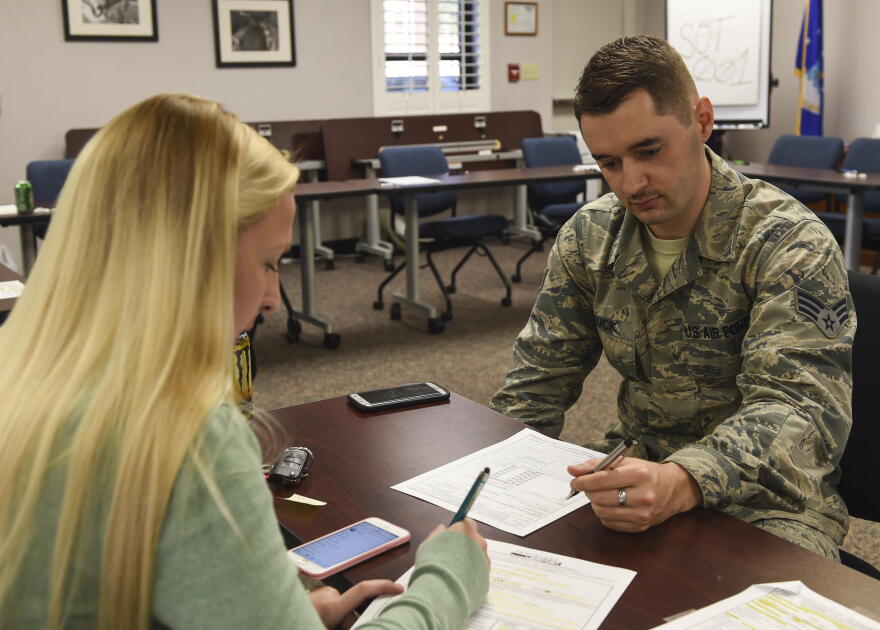 Megan Doty (left), 628th Security Forces Squadron unit program coordinator, files out her travel voucher with Senior Airman James Hauck, 628th Comptroller Squadron financial technician.
