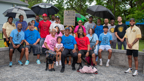 A group of people sit in front of a plaque dedicating the Southside park to Civil Rights icon, Dorothy Bacon