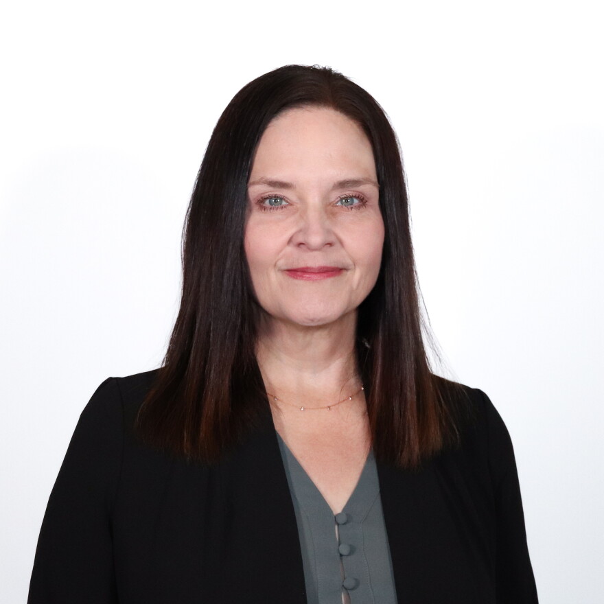 Professional portrait of a woman in a black blazer against a plain white background