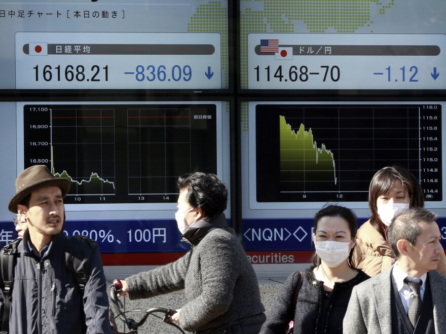 Pedestrians stand outside a securities firm in Tokyo Tuesday. Stocks plunged again in Japan, and the interest rate on the benchmark bond fell below zero.