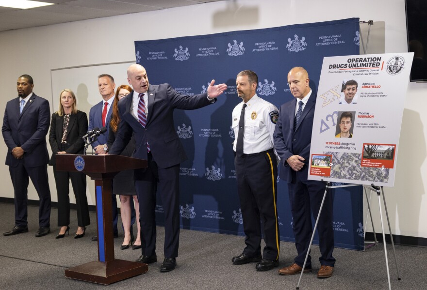 Pennsylvania Attorney General Dave Sunday (center, at podium) points to a poster highlighting the two alleged main suppliers for a cocaine-trafficking ring at Penn State's University Park campus. 