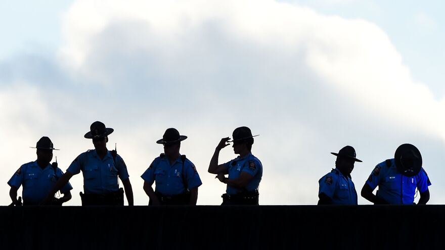 Officers stand guard Tuesday near the site of Brooks' killing in Atlanta. Hours after a prosecutor announced charges against two officers, city authorities noted a wave of callouts in the Atlanta Police Department.