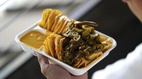 A fan eats nachos during a baseball game between the Texas Rangers and the Baltimore Orioles Saturday, July 20, 2024, in Arlington, Texas. (AP Photo/Jeffrey McWhorter)
