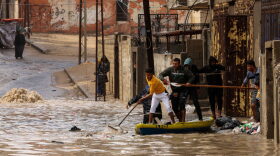 Palestinians ride a paddle board on a flooded street following heavy rain at the Al-Shati refugee camp in the Gaza strip.