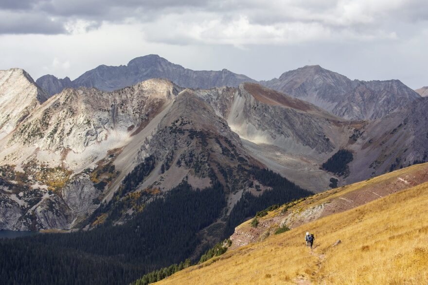 Two hikers climb up Buckskin Pass while completing the Four Pass Loop, a popular backpacking route near Aspen, on Sept. 28, 2022. Backcountry camping permits and fees were implemented in 2023 for overnight stays in popular parts of Maroon Bells-Snowmass Wilderness, such as the Four Pass Loop.