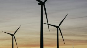 A wind mill supplies water to a stock tank, surrounded by wind turbines of the Smoky Hills Wind Project near Wilson, Kansas. CREDIT: ORLIN WAGNER/AP