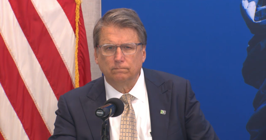 Man scowling in front of flag