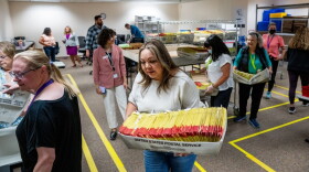 Workers handling U.S. Postal Service trays full of ballots.