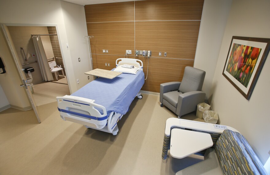 An exam room in a doctors office with a bed and chairs