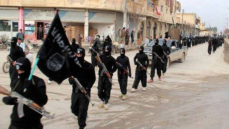 This undated file image posted on a militant website Jan. 14, 2014 shows Islamic State militants marching through Raqqa, Syria.