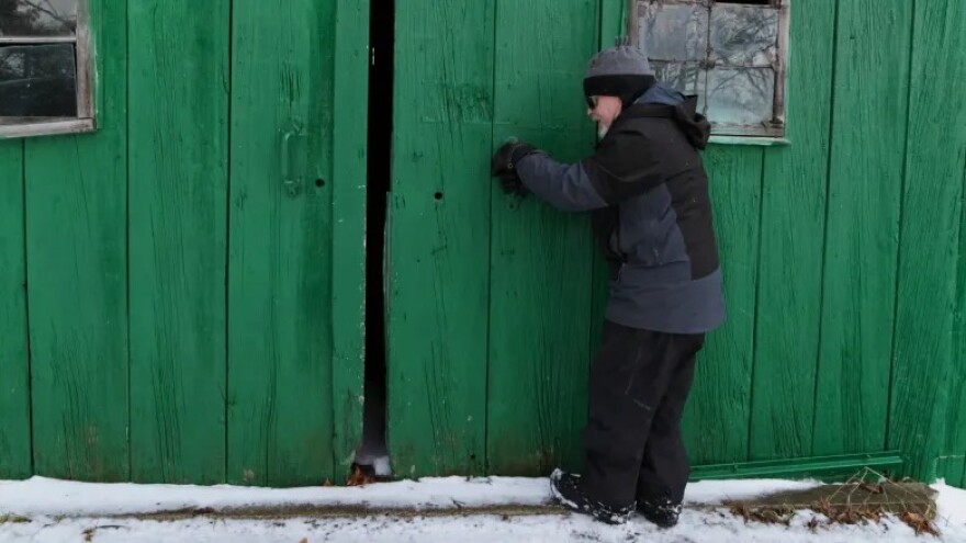 David Weeks opens the barn door on his farm, La Casa Verde, in Cedar. (Photo: Miles MacClure / Northern Michigan Journalism Collaborative)