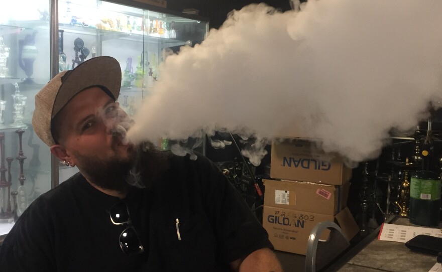 Chris Hiatt blows a large plum of vapor in the basement of The Smoker's Den in downtown Bloomington